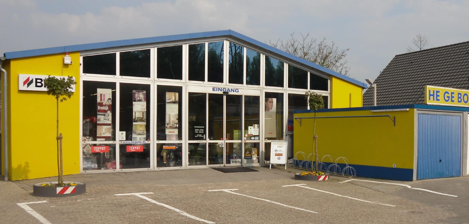 Au&szlig;enansicht zeigt den Haupteingang von HEGEBO Malerbetrieb und Fachgesch&auml;ft in Sch&uuml;ttorf in gelb und blau.